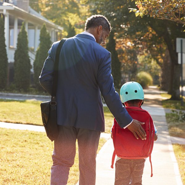 Man and child with backpack walking down the street