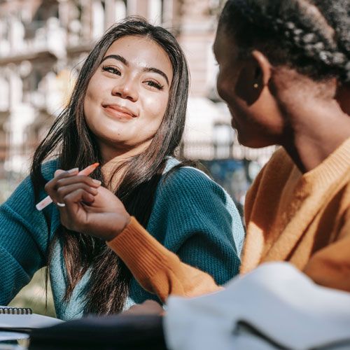 Two women taking notes and smiling at each other