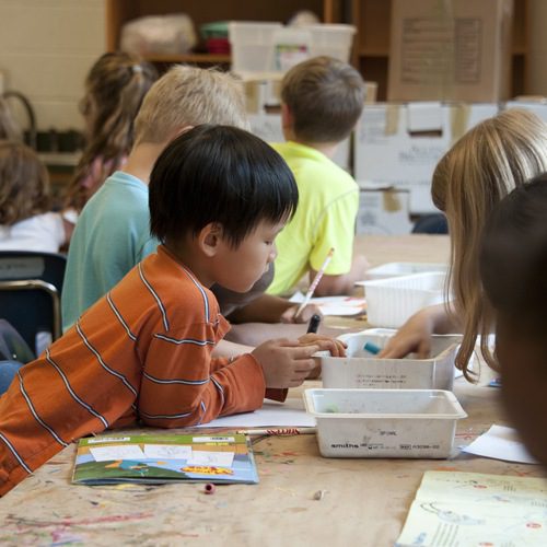 elementary-aged children coloring at a table