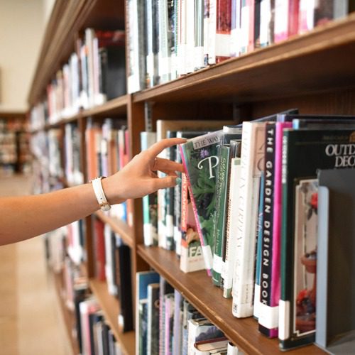 person grabbing a book in a library