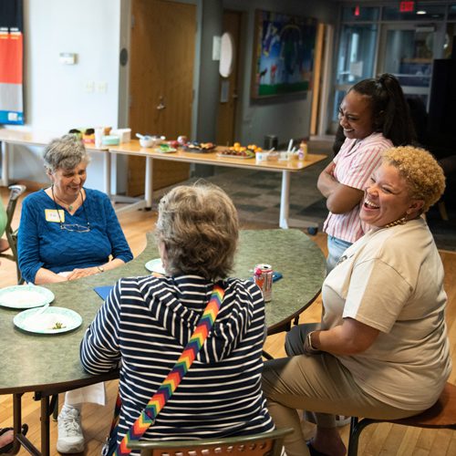 women sitting around a table, laughing together